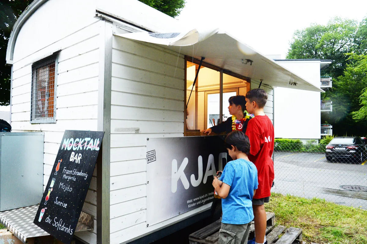 Drei Personen stehen an einer Mocktail-Bar.